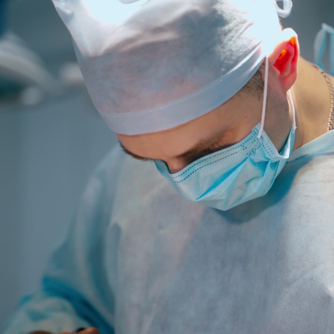 Surgical process in the operating theatre. Male doctor and woman assistant in medical uniform and mask perform an operation at the hospital.
