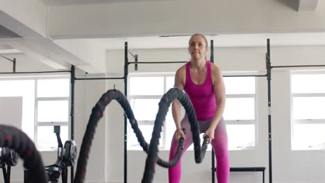 Mujer-Caucásica-Inalterada-Enfocada-Haciendo-Ejercicio-Con-Cuerdas-De-Batalla-En-El-Gimnasio,-En-Cámara-Lenta