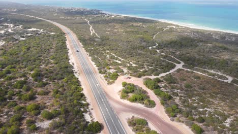 Luftaufnahme-Eines-Autos,-Das-An-Einem-Sonnigen-Tag-Durch-Eine-Schöne-Und-Saubere-Australische-Landstraße-Zum-Ozean-Fährt