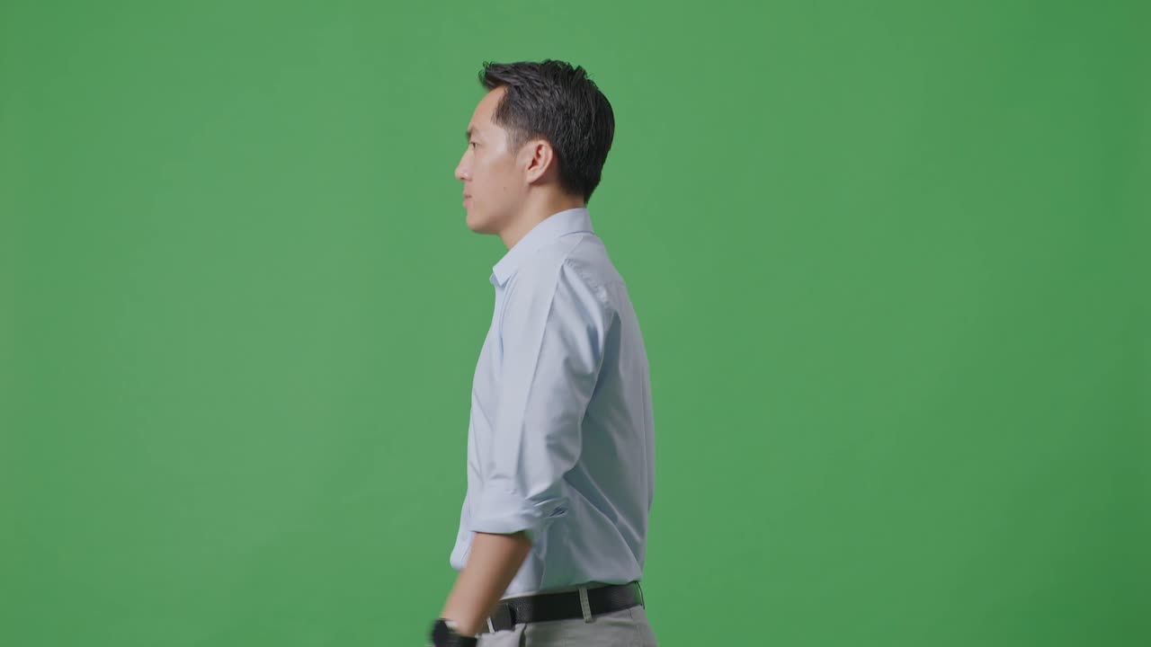 Side View Of Asian Business Man Walking On Green Screen Background In The Studio