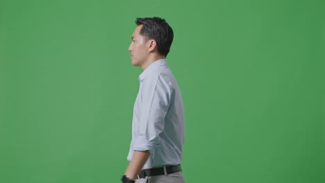 side view of asian business man walking on green screen background in the studio