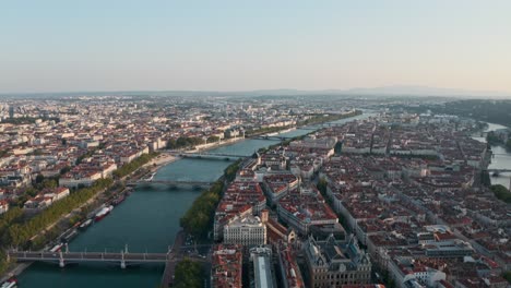 Dolly-forward-drone-shot-over-Rhone-Saone-river-through-Lyon-France-at-sunset