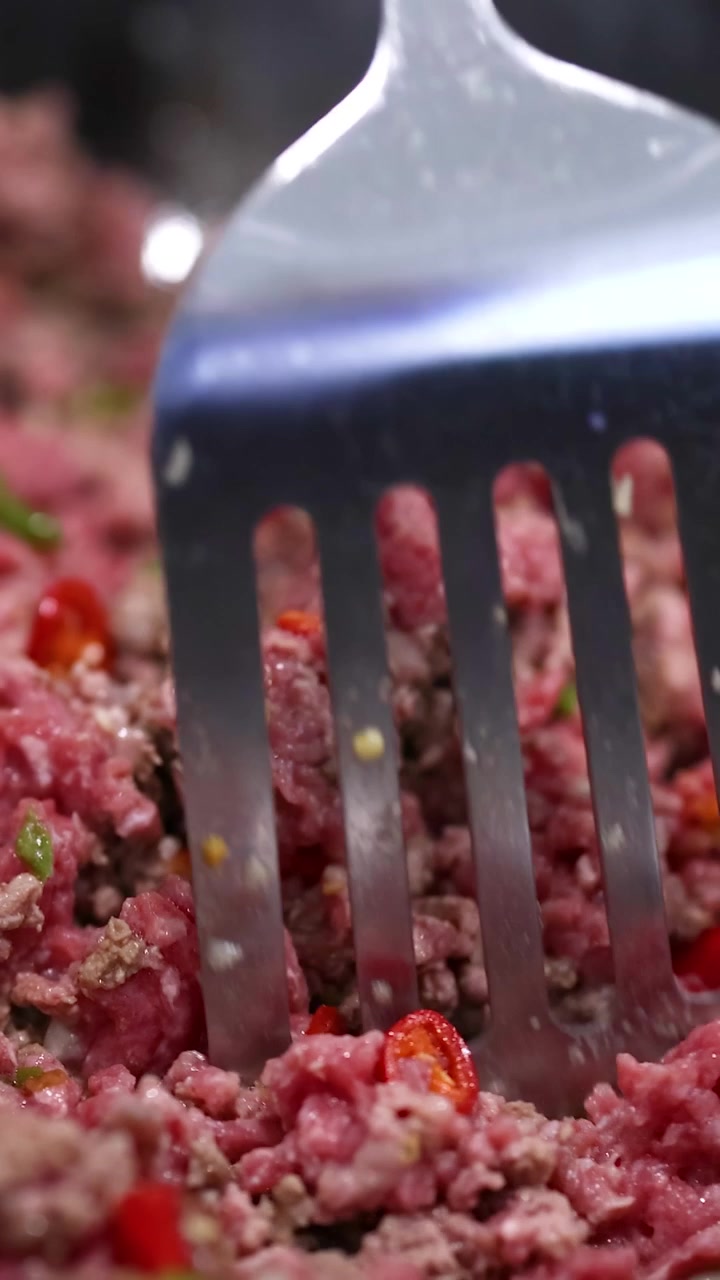 Nahaufnahme der Zubereitung eines Rindfleisch-Pfannengerichts mit roten Paprika in einer Küchenumgebung