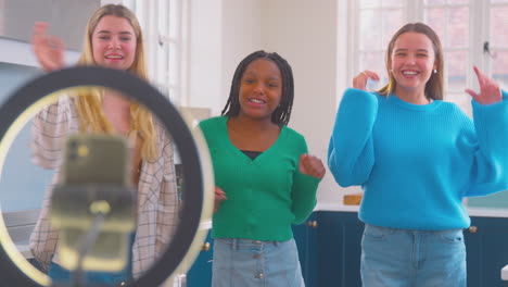grupo de adolescentes en la cocina grabando un video de baile en línea en el teléfono móvil para las redes sociales