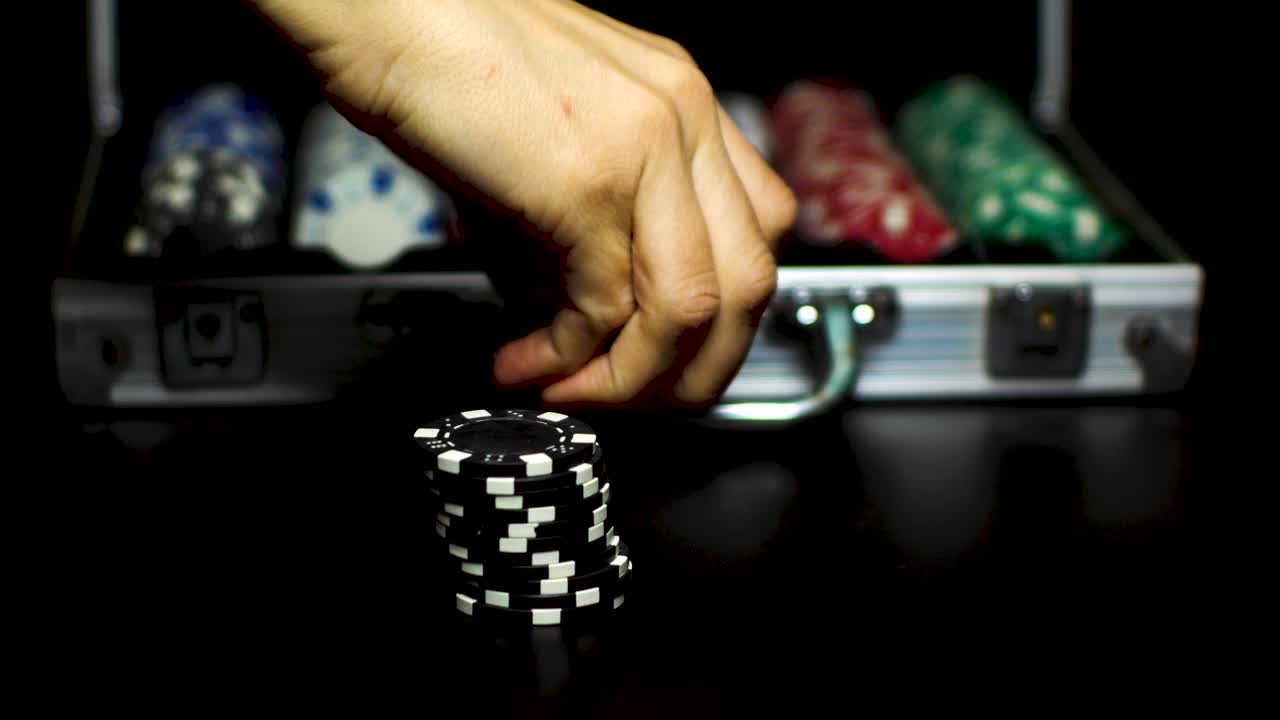 Tangan mengambil tumpukan chip dari meja untuk memasukkannya ke dalam koper poker