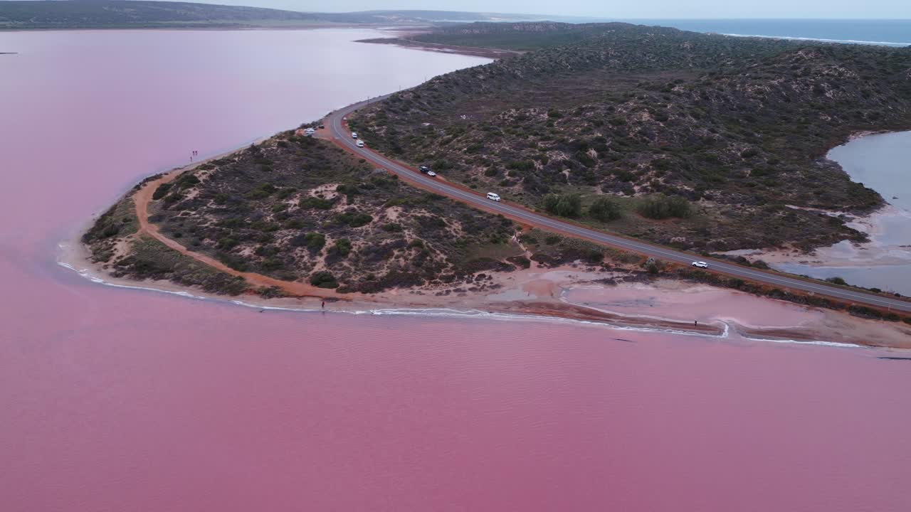 Batı Avustralya, Perth'deki pembe gölün ve Port Gregory Yolu boyunca ilerleyen arabaların havadan çekilmiş görüntüleri