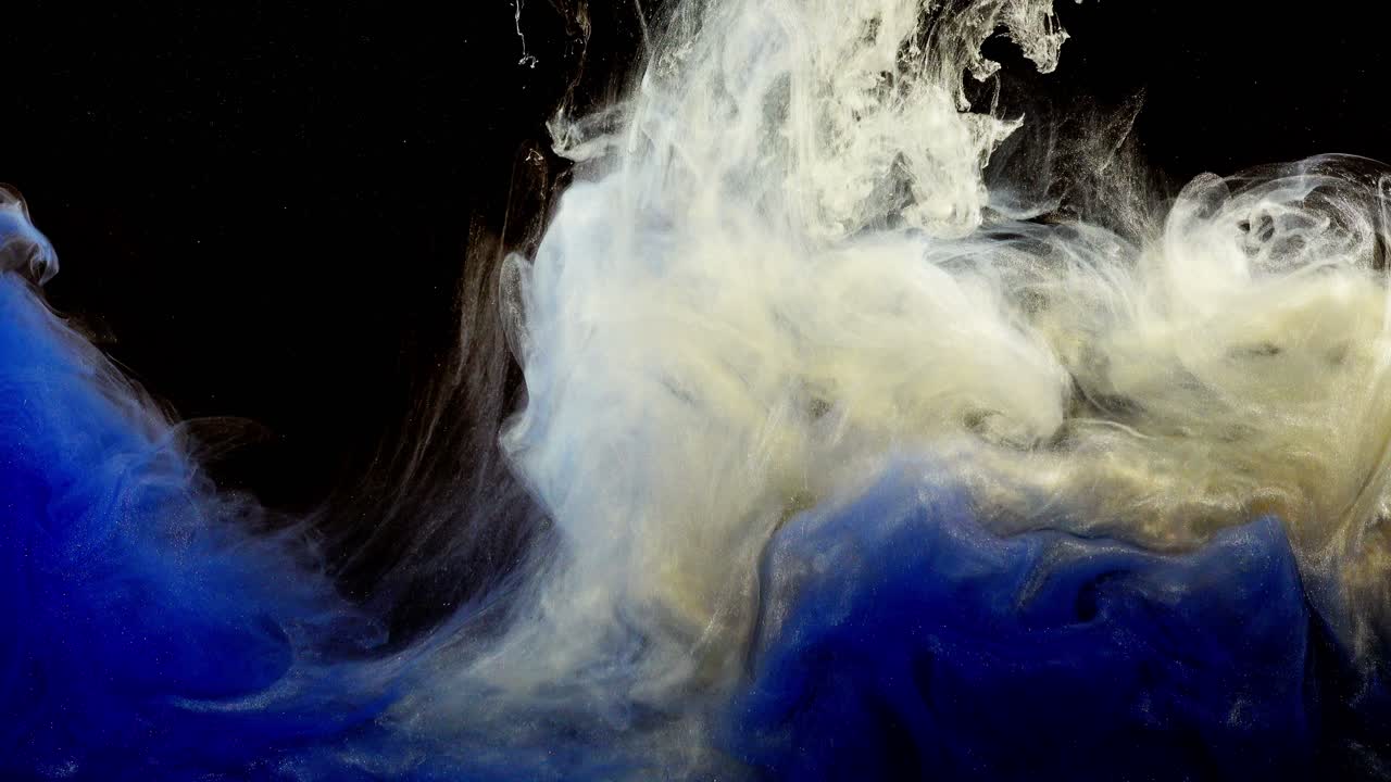 Encre bleue, blanche et or se mélangeant dans l'eau sur fond noir.