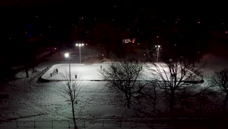 drone flying around an outdoor municipal hockey rink in snowy montreal, quebec, canada