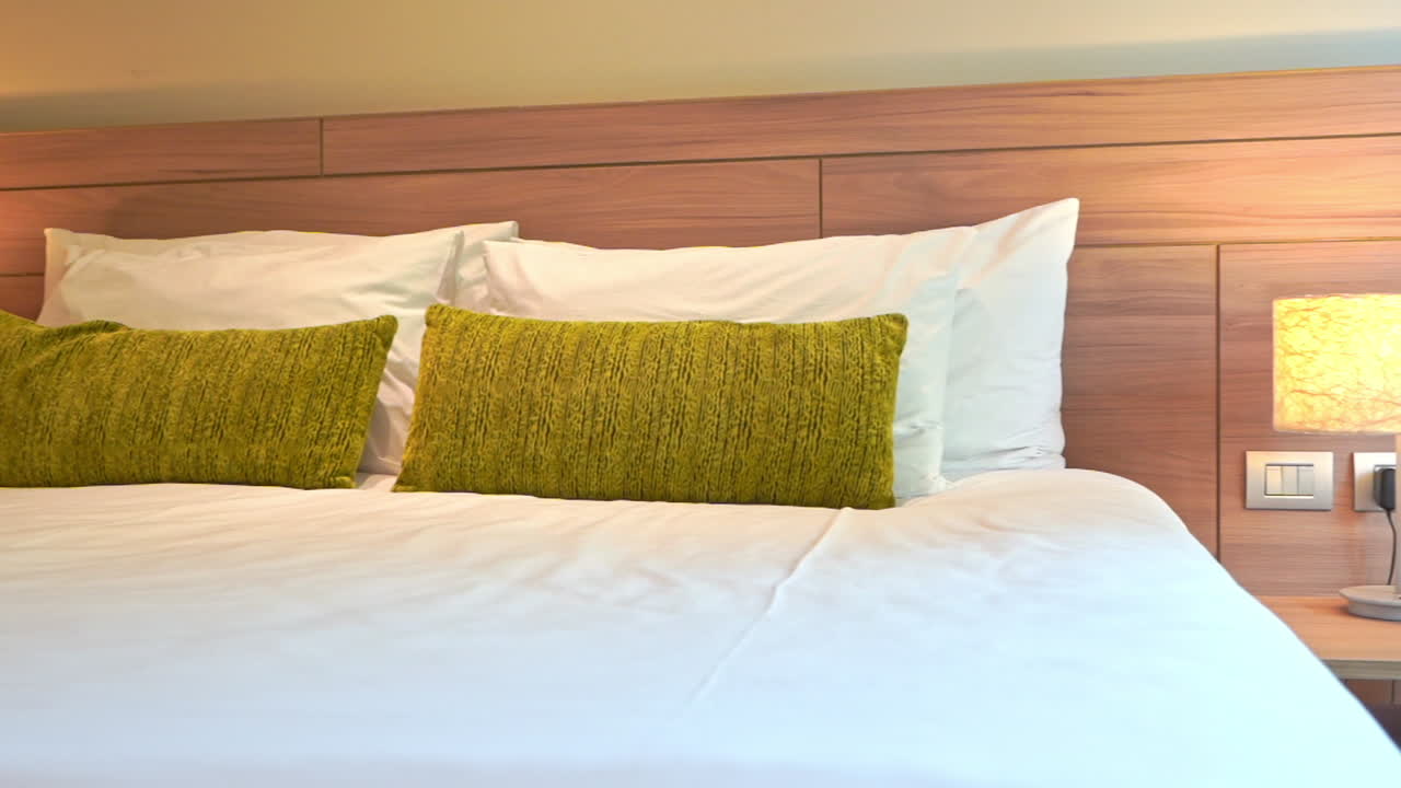 녹색 던지기 베개로 장식 된 침대를 가로질러 왼쪽에서 오른쪽으로