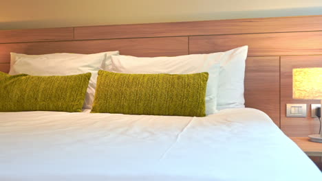 pan left to right across a bed decorated with green throw pillows