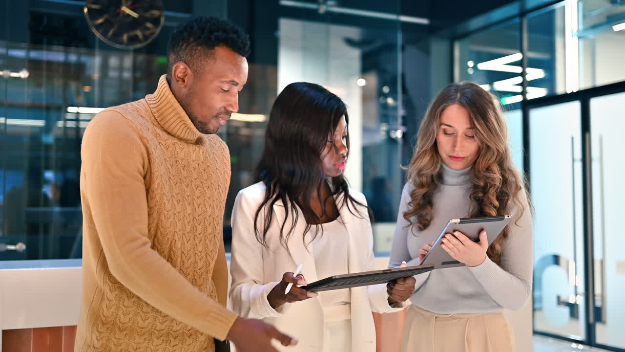 Multiracial group of workers in an office discussing business using tablets
