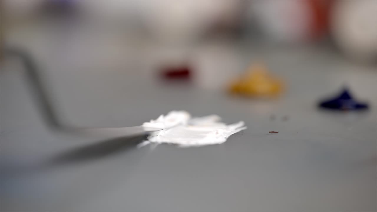 Spatola da pittore che taglia pezzi di pittura e li mescola per unirli con pittura bianca.