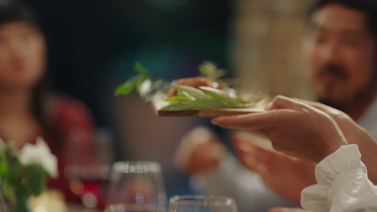 amigos felices celebrando en una cena comiendo comida mediterránea compartiendo plato sentados en la mesa disfrutando de la fiesta de la noche 4k
