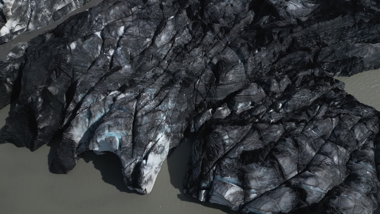 Drone top down pan across broken dirty ice glaciers melting, aerial backdrop