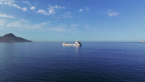 flying towards the barge floating in the calm sea in daytime