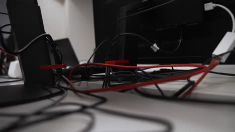 close up behind computer monitor stand of cables, ethernet, power leads