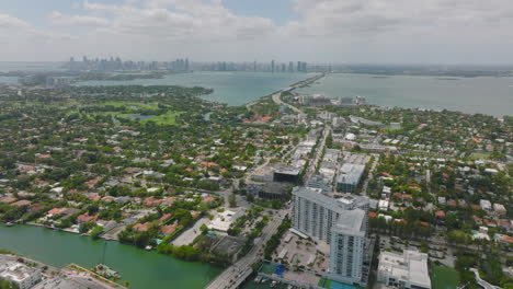 High-angle-view-of-residential-neighbourhood-with-houses-surrounded-by-trees-and-green-vegetation.-Tilt-up-reveal-cityscape.-Miami,-USA