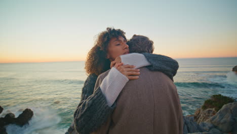 peaceful lovers bonding sunset on seacoast closeup. diverse spouses embracing