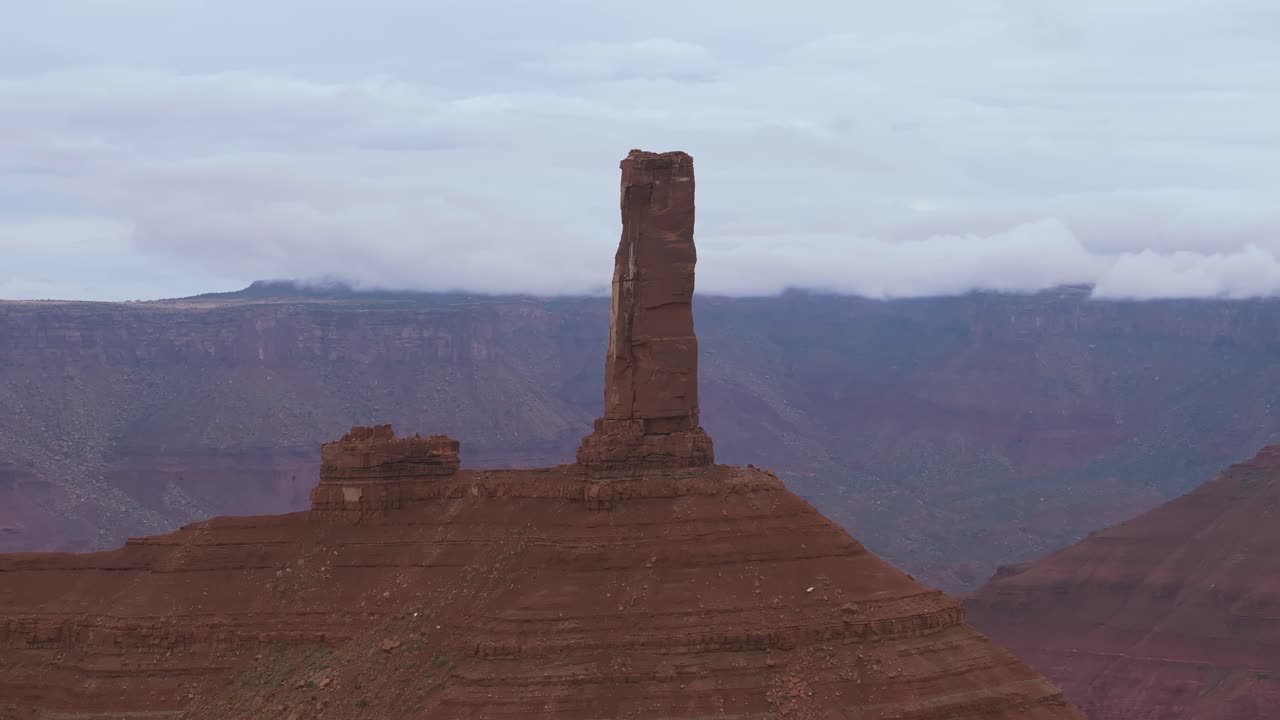 Iconic red rock spire under cloudy sky in Moab's desert landscape