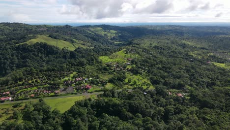 aerial view moving forward shot, houses in the foothills of la tigra rain forest in costa rica, bright blue sky in the background