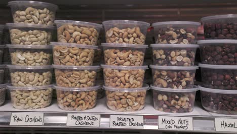 mixed nuts peanuts and cashew snacks sit on a supermarket shelf in plastic containers