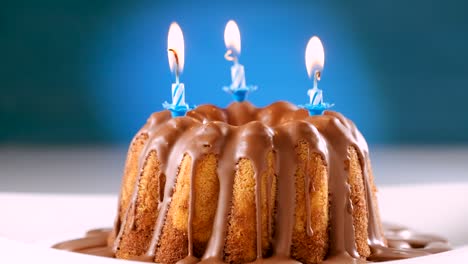 burning blue birthday candles on marble cake with chocolate nougat icing