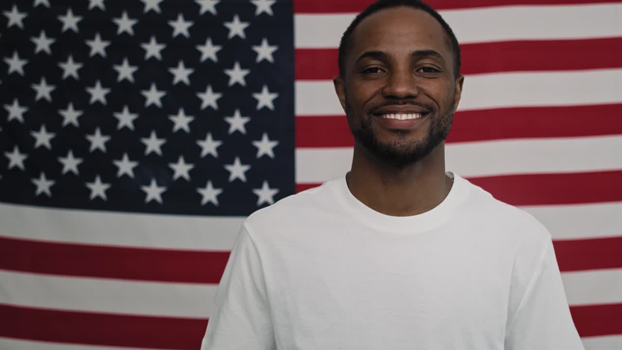 Video di uomo di colore allegro su sfondo con bandiera americana