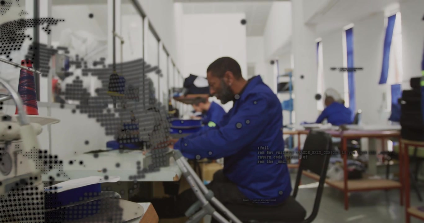 Camera pulling back, globe overlay receding, worker operating machine assembling parts in factory