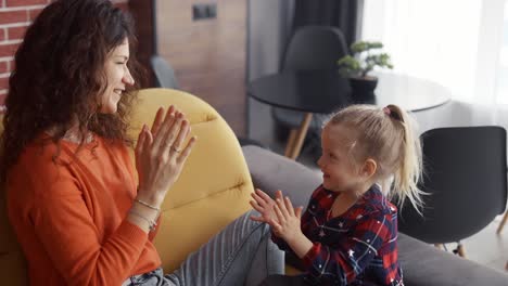 Mutter-Spielt-Mit-Ihrer-Tochter-Auf-Der-Couch-Und-Klatscht-In-Die-Hände