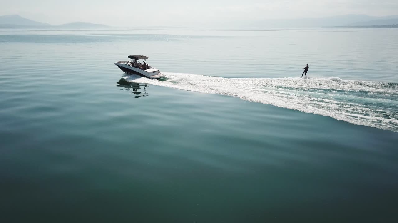 Seorang atlet wakeboard sedang bersenang-senang di belakang perahu bermotor di tengah Danau Jenewa.