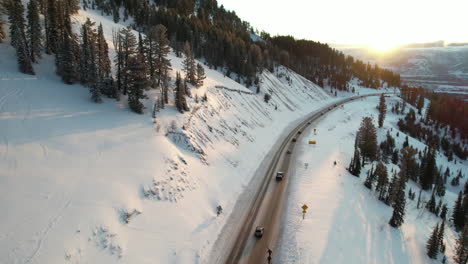 Luftaufnahme-Des-Straßenverkehrs-In-Verschneiter-Berglandschaft-Bei-Sonnenuntergang