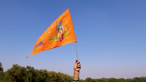 holy-saffron-flag-with-lord-rama-idol-holing-in-hand-with-bright-blue-sky-background-at-day