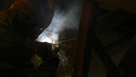 sparks fly as a factory worker welds steel framing in an industrial machine shop