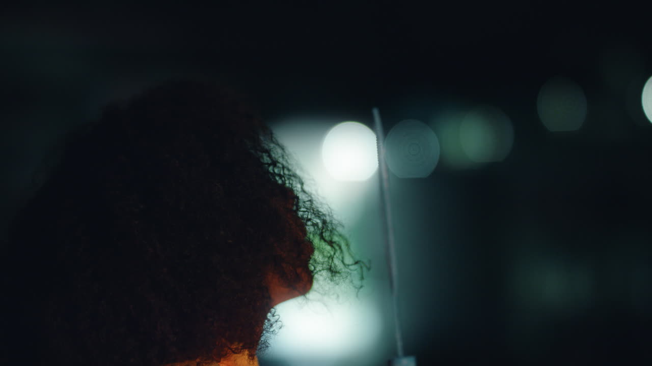 hermosa joven afroamericana soplando burbujas en el techo por la noche disfrutando de una noche lúdica con luces bokeh en el fondo