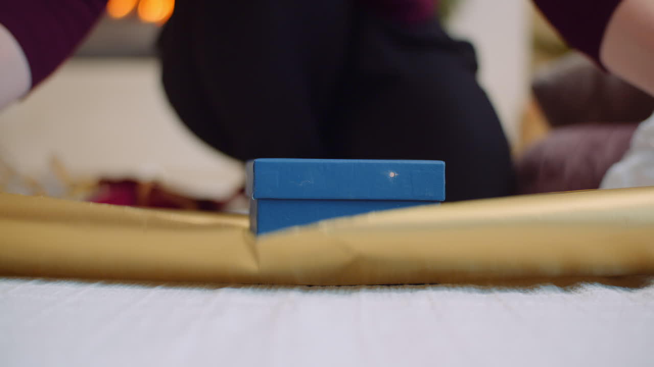 황금 선물 종이로 크리스마스 선물을 포장하는 여자