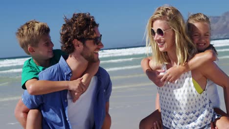 Parents-giving-piggyback-ride-to-their-children-at-beach