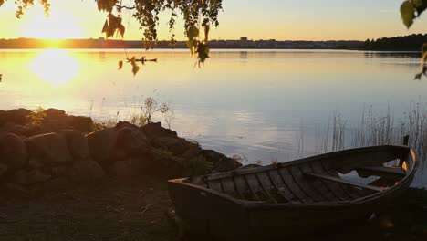 Altes-Boot,-Ruhiges-Wasser-Und-Kajakfahrer-Bei-Sonnenuntergang,-Goldenes-Stundenmeer,-Rustikales-Boot-Und-Kajak