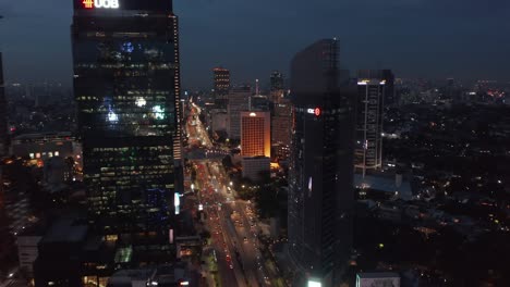 aerial dolly shot flying towards skyscrapers above busy night traffic on the highway in jakarta, indonesia