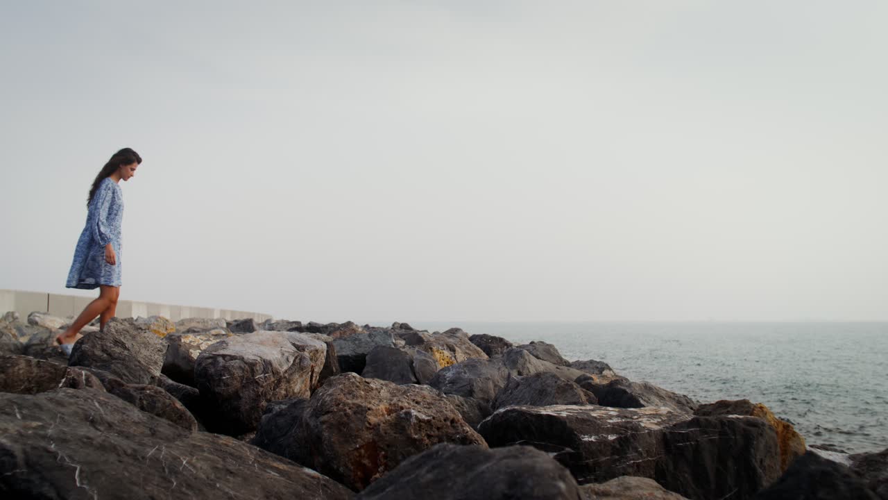 Donna che cammina sulle rocce vicino all'oceano