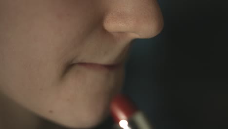 primer plano de una mujer joven que aplica lápiz labial rojo en sus labios