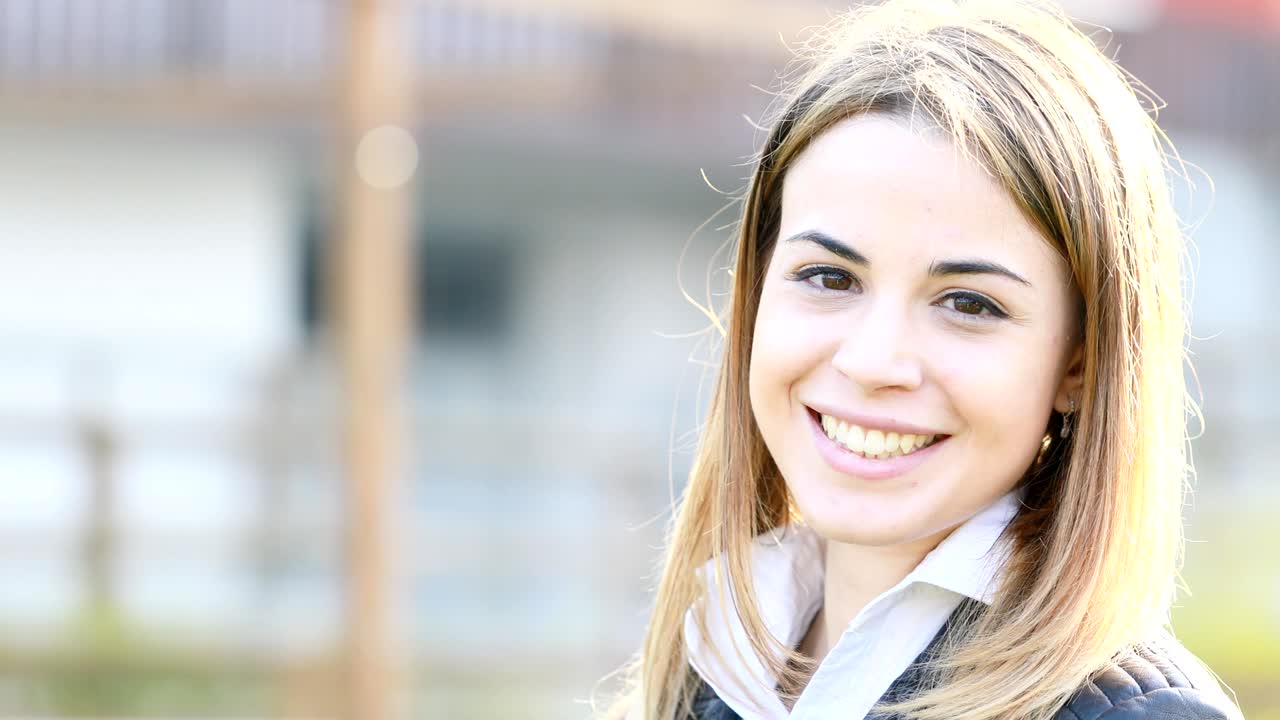 woman outside turns to camera and smiles