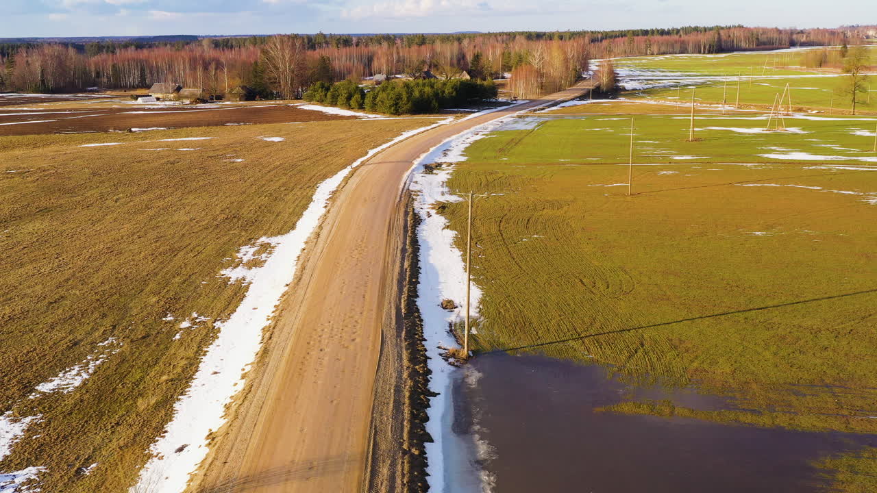 сельскохозяйственные угодья с тающим снегом в солнечный весенний день, вид с дрона