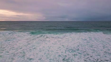 Foamy waves crashing shoreline at tranquil twilight aerial view. Ocean force
