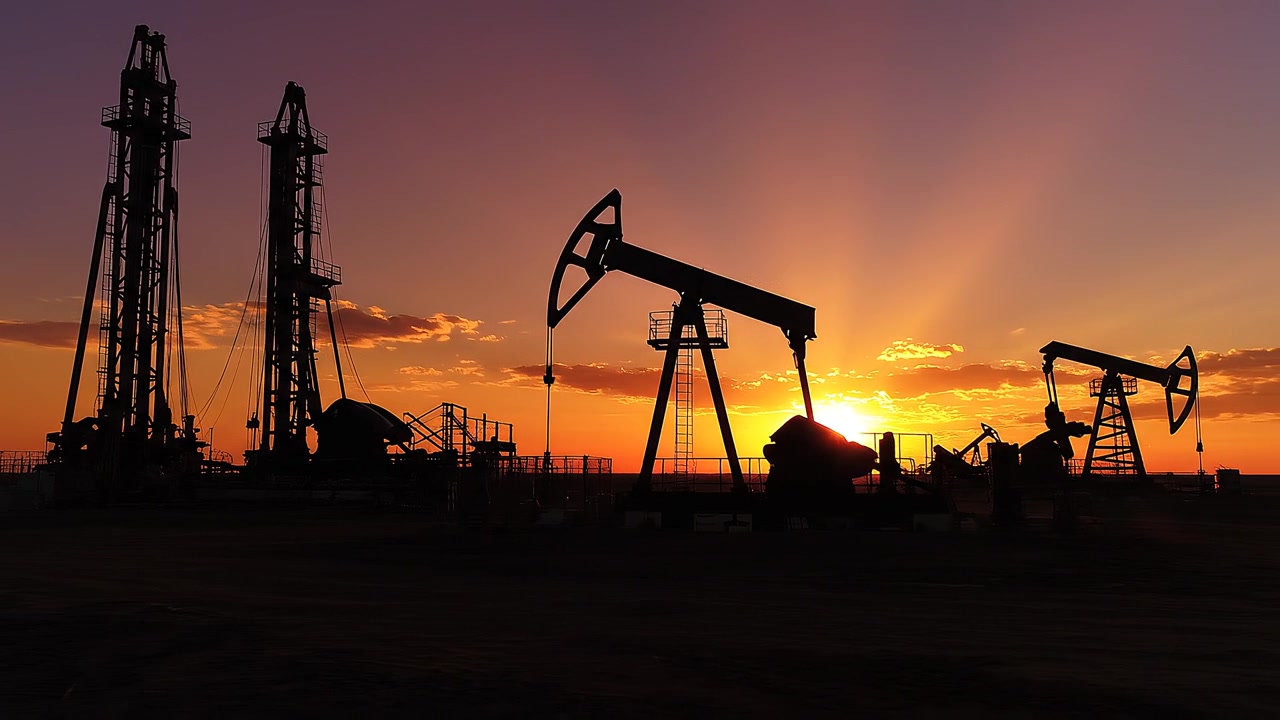 Siluetas de balancines petroleros y plataformas de perforación al atardecer