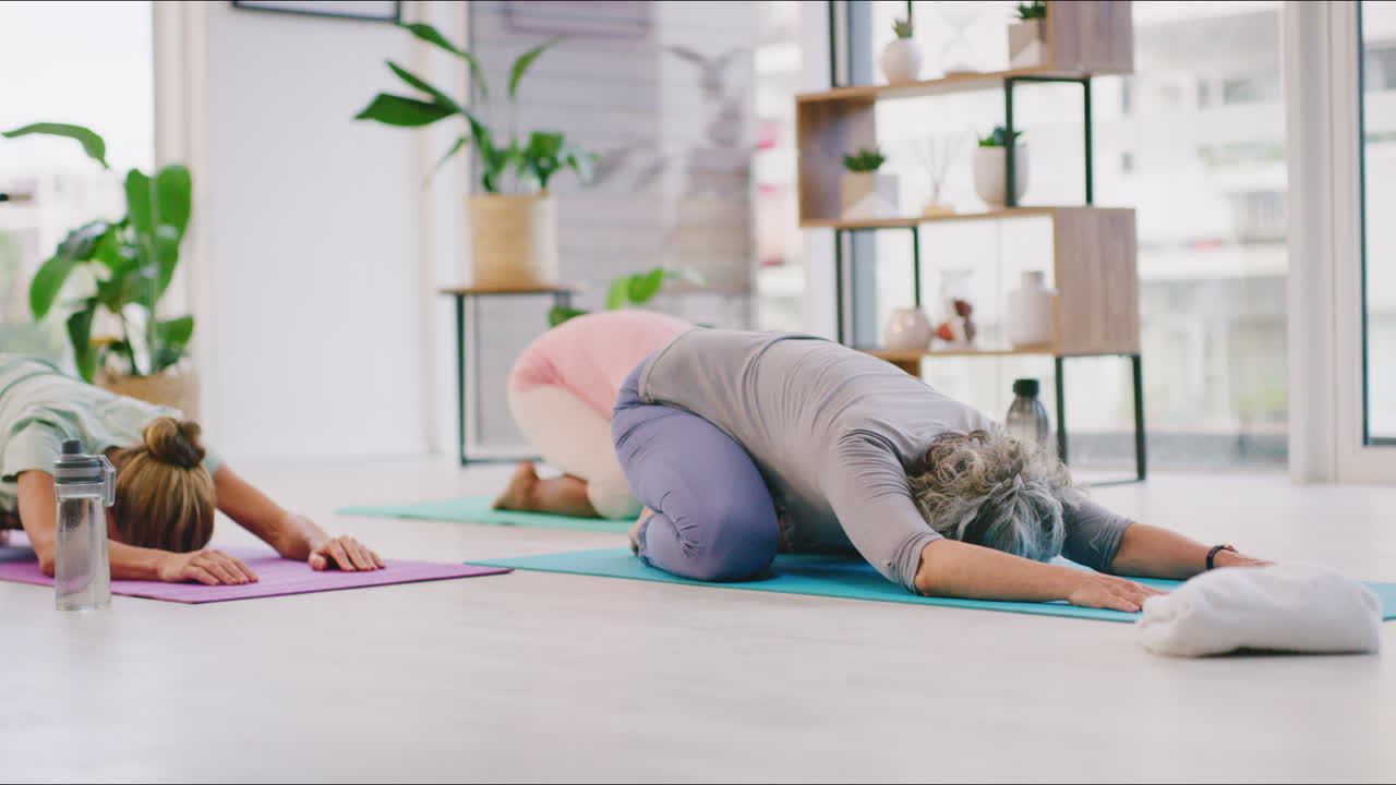 Donne mature che praticano yoga in posizione del bambino in un ambiente zen.