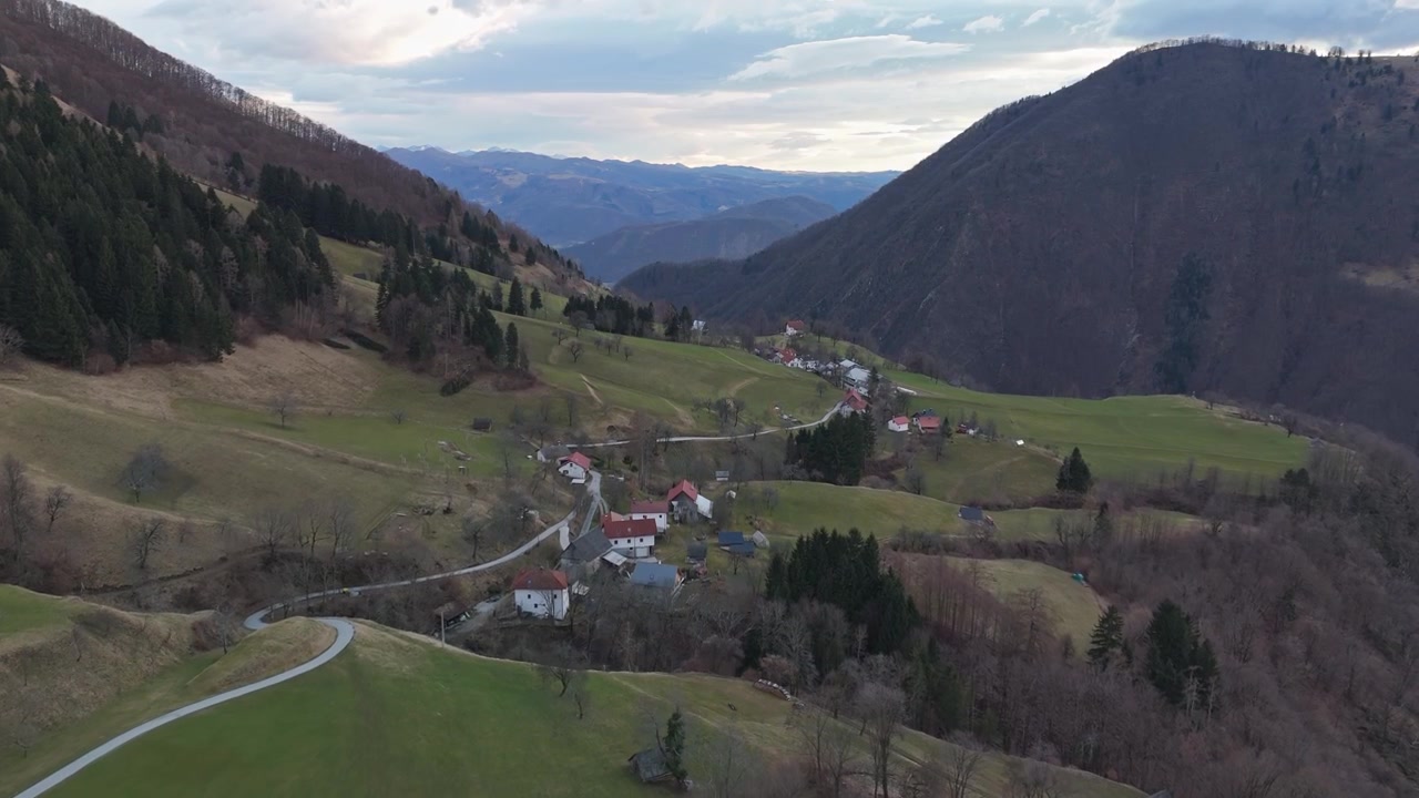 Slovenya, Triglav Milli Parkı'ndaki Čadrg köyü, Julian Alpleri'nde alpin çayırları, orman ve tarım arazileriyle çevrili olup, havadan görünümde kırmızı çatılı evler ve virajlı yollarla dikkat çekiyor.