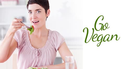 animación de texto vegano en verde sobre mujer caucásica sosteniendo un tenedor con ensalada