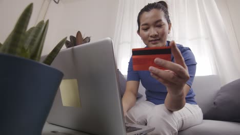 empresaria asiática está usando tarjetas para pagar compras en línea en una computadora portátil