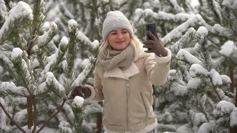 a girl in white clothes stands near a pine tree in the snow.