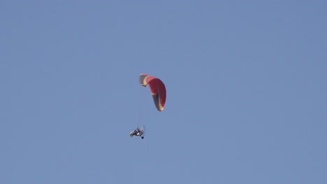 competitive paraglider gliding against a blue sky, sport competition